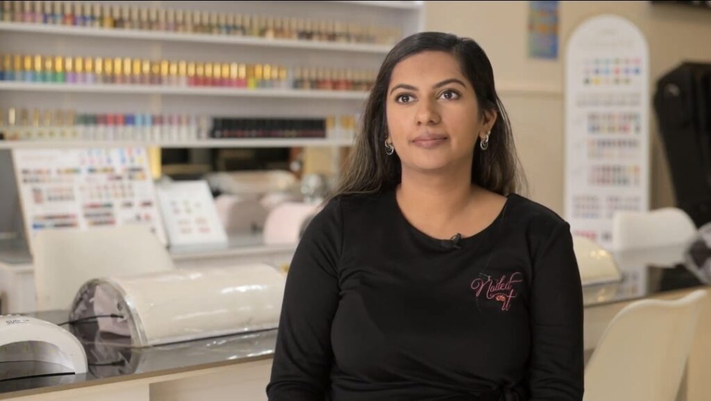 Woman stands in front of a nail salon