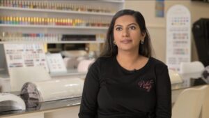 Woman stands in front of a nail salon